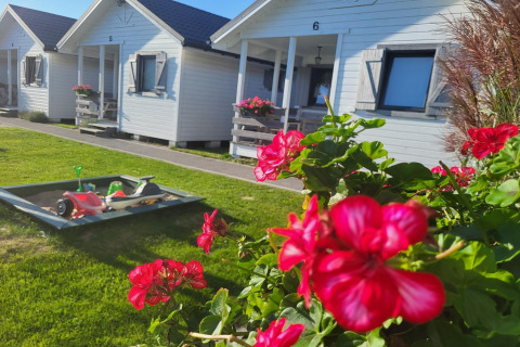 Rode bloemen op de voorgrond en witte vakantiewoningen met speelzandbak achteraan in Gąski, Denemarken.