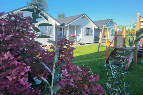 Vakantiehuisjes in Gąski, Denemarken, met kleurrijke bloemen en een speeltuin op het grasveld.