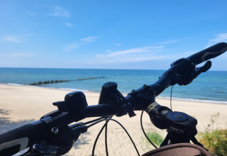 Bicycle handlebars overlooking the beach and sea at 'Holiday cottages in Gąski' in Denmark on a sunny day.