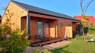 Día soleado en Twin single-storey cottages Jarosławiec con cabañas de madera y césped verde cuidado.