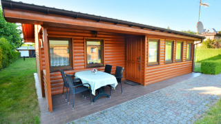 Log cabin with outdoor dining area and garden at House in Rosnowo, featuring sunny and clear weather.