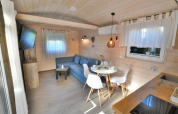 Modernes Ferienhaus mit heller Holzverkleidung, gemütlicher Sitzecke und Essplatz für zwei Personen.