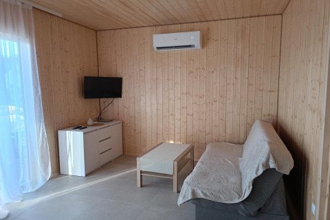 Moderne woonkamer met houten wanden, bank, salontafel, tv, dressoir en airco in de Jarosławiec cottages.