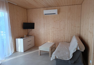 Moderne woonkamer met houten wanden, bank, salontafel, tv, dressoir en airco in de Jarosławiec cottages.
