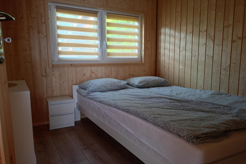 Slaapkamer met tweepersoonsbed en houten wanden in Twin single-storey cottages Jarosławiec, Denemarken.