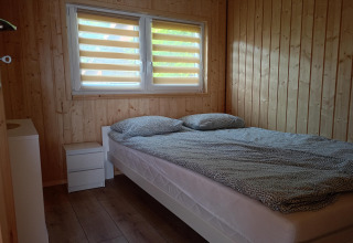 Soveværelse med dobbeltseng, trægulve og panelvægge i Twin single-storey cottages Jarosławiec, Danmark.