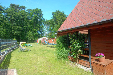 Solrig have ved Twin single-storey cottages Jarosławiec med gyngestativ, liggestole og rød træhytte, Danmark.