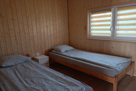 Two single beds with grey bedding in a wooden room at Twin single-storey cottages Jarosławiec in Denmark.