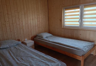 To enkeltsenge med grå sengetøj i et træbeklædt værelse på Twin single-storey cottages Jarosławiec, Danmark.