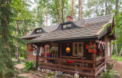 Knus houten vakantiehuis in het bos, met gezellige veranda en felgekleurde hangbloembakken buiten.
