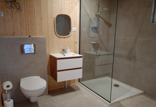 Modern bathroom in Twin single-storey cottages Jarosławiec, Denmark, with glass shower and wooden walls.