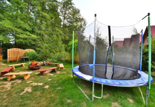 Outdoor area at Twin single-storey cottages Jarosławiec, Denmark, with trampoline, firepit, and wooden benches.