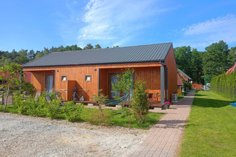 Twin single-storey wooden cottages with black roofs and garden area at Jarosławiec Lodge in Denmark.