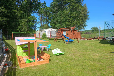 Udendørs legeplads ved Twin single-storey cottages Jarosławiec med gynger, sandkasse og legeudstyr.