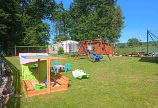 Buiten speeltuin bij Twin single-storey cottages Jarosławiec met schommels, zandbak en speelhuisje.