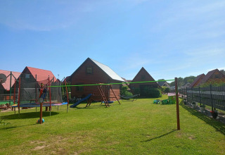 Zonnige speeltuin met houten huisjes in de tuin bij Twin single-storey cottages Jarosławiec in Denemarken.