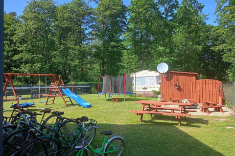 Playground with swings, slide, trampoline, and bikes at Twin single-storey cottages Jarosławiec in Denmark.