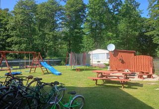 Speelplaats met schommels, glijbaan, trampoline en fietsen bij Twin single-storey cottages Jarosławiec in Denemarken.