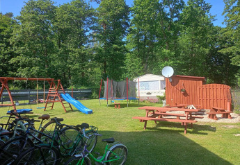 Parque infantil con columpios, tobogán, cama elástica y bicicletas en las cabañas Jarosławiec en Dinamarca.