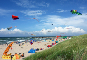 Bunte Drachen fliegen über einem Strand mit Zelten und Dünen bei Twin single-storey cottages Jarosławiec.