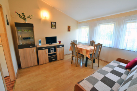 Wohnzimmer im House in Rosnowo mit Esstisch, Sofa und großen Fenstern mit Gardinen, Dänemark.