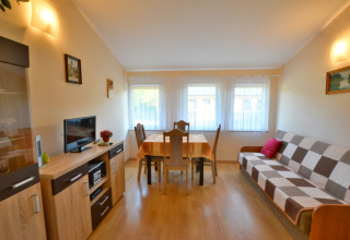 Heller Wohnraum im House in Rosnowo, Dänemark, mit Sofa, Esstisch und Schrankwand in warmer Atmosphäre.