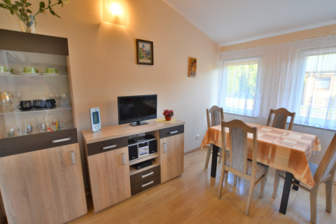 Heller Essbereich mit Esstisch, vier Stühlen, Vitrine und Fernseher im House in Rosnowo in Dänemark.
