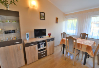 Zona pranzo luminosa con tavolo, quattro sedie, mobile e TV nella House in Rosnowo in Danimarca.