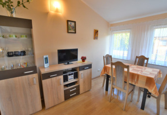 Salle à manger lumineuse avec table, quatre chaises, buffet et TV au House in Rosnowo au Danemark.