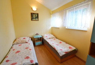 Helles Zimmer im House in Rosnowo mit zwei Einzelbetten, gelben Wänden und floraler Bettwäsche.