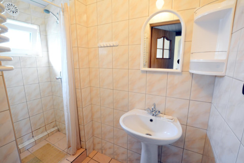 Bright bathroom at House in Rosnowo, Denmark, featuring a tiled shower, washbasin, mirror and cream tiles.