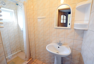 Baño luminoso en House in Rosnowo, Dinamarca, con ducha alicatada, lavabo, espejo y paredes de azulejos claros.
