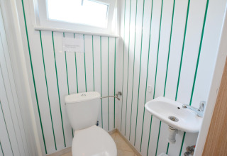 Lille badeværelse i House in Rosnowo-lodgen i Danmark med toilet og lille håndvask ved siden af.