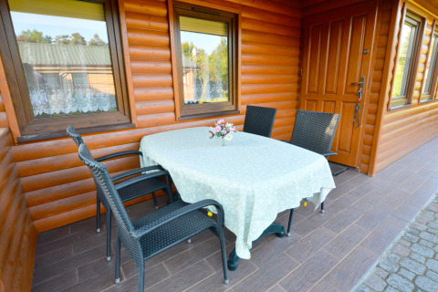 Terrazza esterna presso House in Rosnowo, Danimarca, con tavolo, quattro sedie e vaso di fiori al centro.