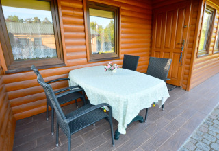 Terrasse am House in Rosnowo in Dänemark mit gedecktem Tisch, vier Stühlen und Blumen in der Mitte.