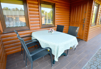 Buiten terras bij House in Rosnowo in Denemarken met een tafel, vier stoelen en een bloemenvaas.