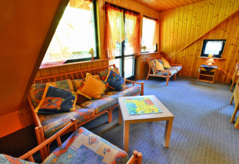 Knusse lodge zithoek met veel licht, houten wanden, gekleurde zetels en grote ramen.