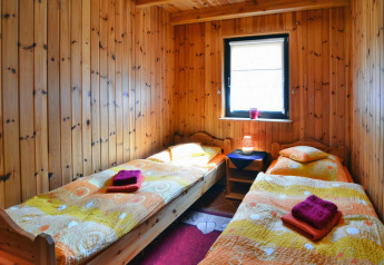 Knusse kamer in een lodge met twee enkele bedden, houten wanden en een raam met zicht naar buiten.