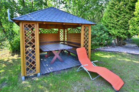 Gazebo in legno con tavolo, panca e sdraio rossa in giardino al Holiday home for 3 people Kołobrzeg.
