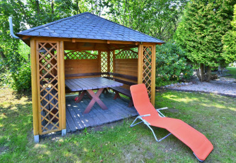Houten tuinpaviljoen met tafel, bank en rode ligzetel bij Holiday home for 3 people Kołobrzeg.