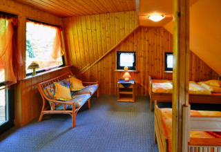 Acogedora casa de madera Holiday home for 3 people Kołobrzeg con dos camas, sofá y decoración alegre.