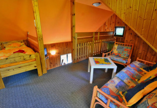 Acogedora buhardilla en un albergue con cama individual, sofá, mesa de centro y paredes de madera.