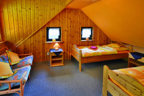 Camera accogliente in un rifugio con pareti in legno, due letti singoli e una zona relax con divano.