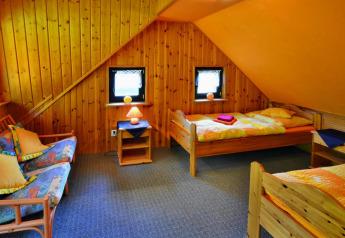 Gezellige lodgekamer met houten wanden, twee eenpersoonsbedden, bank en sfeervolle verlichting.