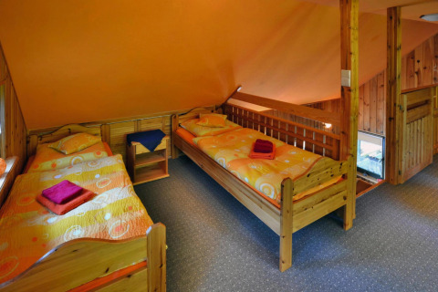 Room with three single beds, orange walls, wooden furniture, and colorful bedding in a holiday home.