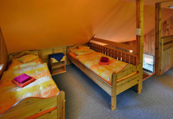 Kamer met drie eenpersoonsbedden, oranje muren, houten meubels en kleurrig beddengoed in een vakantiehuis.
