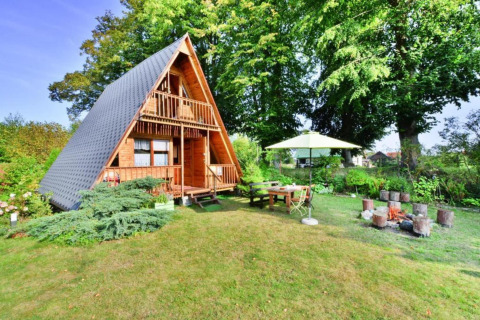 Sommerhus med A-ramme, have, terrasse, bålplads og parasol i grønne omgivelser i Danmark.