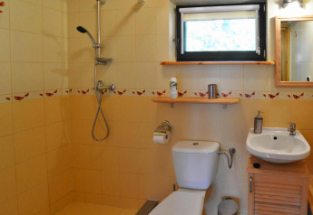 Netjes lodgebadkamer met douche, toilet en wastafel, met vlindertegels als decoratie aan de muren.