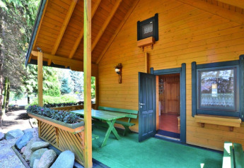 Vakantiehuis in hout met overdekt terras, groene zitbank en bloemen in Kołobrzeg, Denemarken.