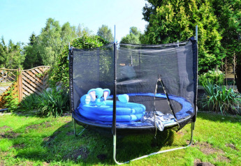 Trampoline met veiligheidsnet en blauw kinderbad in de tuin bij een vakantiehuis in Kołobrzeg.